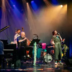 En jazzkvartett spelar på scenen, en del av stockholms jazzfestival program. Sångerskan i glittrig klänning, trumpetare, basist och pianist.