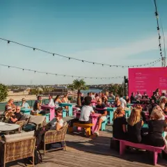 Folk njuter av solen och utsikten på en takbar i Stockholm. En perfekt plats för ett sommarevenemang.