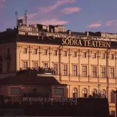 Södra Teatern, en ikonisk byggnad vid Mosebacke, badar i kvällssolens rosa sken.