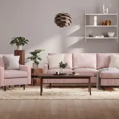 Ett mysigt rosa vardagsrum med en stor soffa, fåtölj, soffbord och en fluffig matta. Växter och konst ger liv åt rummet.