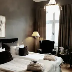 Ett elegant hotellrum med dubbelsäng, konst på väggen och en kristallkrona. Mysig hotellrum inredning med fåtöljer och en champagnehink.