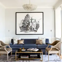 Ett elegant vardagsrum med blå inredning, en mörkblå soffa, antika stolar och en stor svartvit tavla.