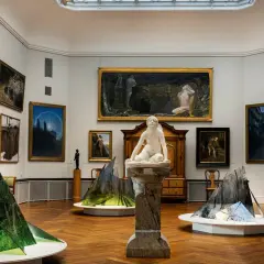 Konsthall med målningar och skulpturer. I förgrunden syns moderna installationer som speglar naturen. Thielska museet bjuder på en fascinerande blandning av gammalt och nytt.