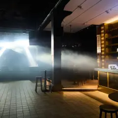 Scenljus och rök fyller lokalen på slaktkyrkan Stockholm. En bar i guld och svart syns till höger.