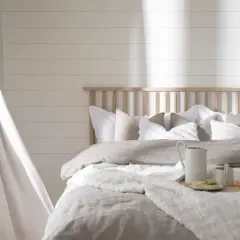 Mysigt sovrum med ljusa textilier och en trägavel. Perfekt sovrum inspiration för en lugn oas.