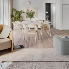 Ett ljust och luftigt vardagsrum med matplats i klassisk nordisk design. En bekväm fåtölj och en grön pall skapar en inbjudande atmosfär.