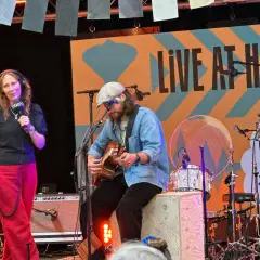 Jens Hult konsert med en kvinna som håller mikrofon och en man som spelar gitarr på scenen.