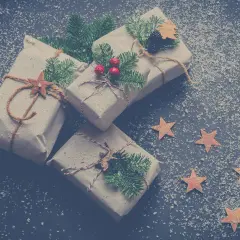 Julklappar inslagna i brunt papper, dekorerade med granris och stjärnor, redo för Siggesta Gård julmarknad.