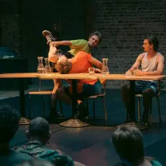 Akrobater på en scen vid ett bord, en del av föreställningen på Stockholm Fringe Festival.