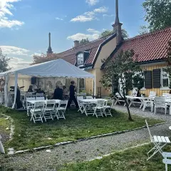 Festligt dukat utanför Ekermanska malmgården med tält, bord, stolar och ett liveband.