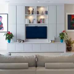 Modernt tv-rum med en stor mediabänk, konstverk och bekväm soffa.