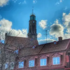 Engelbrekts kyrka reser sig mot en dramatisk himmel med moln. Kyrktornet har en klocka och en grön kupol.