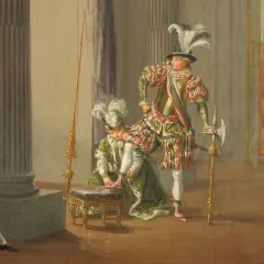 Scen från teater kungen där en person får sina skor på sig. Flera figurer i historiska dräkter.
