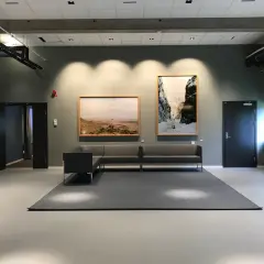 Väntrum med konstverk på väggarna, en soffgrupp och en matta. Kanske en del av konstakademien Stockholm.