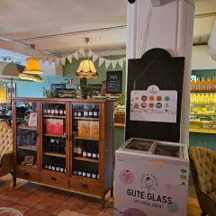 Mysigt café med en gul sammetssoffa, ett vitrinskåp fyllt med godsaker och en frys med "Gute Glass" Gotländsk godhet.