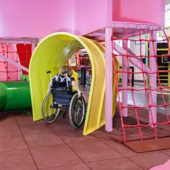 En person i rullstol navigerar genom en färgglad lekplats på Teknikmuseet Stockholm.