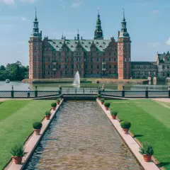 En imponerande utsikt över de kungliga slotten med en kanal som leder fram till en bro och slottet i bakgrunden.