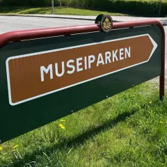 Skylt som pekar mot Museiparken Stockholm. En grön skylt med en brun pil och texten "MUSEIPARKEN" i vitt.