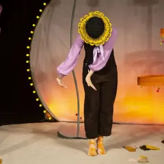 En docka med solros-huvud på scenen, en del av dockteater Stockholm.