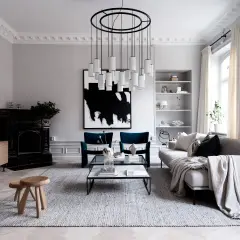 En modern skandinavisk inredning med en abstrakt skulptur som konstverk. En elegant taklampa och en svart öppen spis bidrar till rummets karaktär.