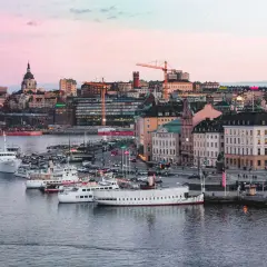 Vackert ljus över vattnet och båtar vid kajen i Stockholm. Staden ser inbjudande ut, redo för äventyr imorgon.