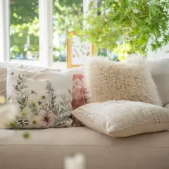 Mysiga kuddar i soffan inspiration: en blommig kudde med bin, en fluffig beige kudde och en texturerad ljus kudde skapar en ombonad känsla.