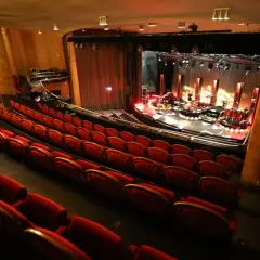 Tomma röda sammetsstolar i en teater, redo för publiken. Scenen är upplyst med instrument och redo för en konsert. En av många fina konsertlokaler i Stockholm.