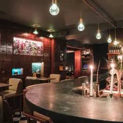 Mysig bar i Stockholm med mörka trädetaljer, gröna marmorbänkar och levande ljus. Perfekt för en romantisk date night.