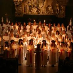 Stor kör av barn och ungdomar i vita dräkter med ljus och stjärnhattar under en luciakonsert 13 december i Stockholm.