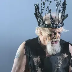 En skådespelare som Kung Lear på Dramaten, med en taggig, svart krona och trasiga kläder.