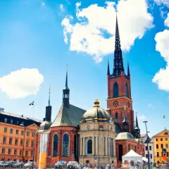 Stadshuset i Gamla Stan, Stockholm, med sina torn och en gul byggnad under en blå himmel med moln.