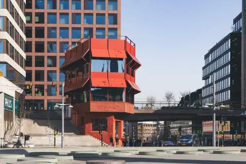 Rött, unikt hus vid Sergels torg, med trappor och moderna byggnader runtom. En plats för bio och möten.