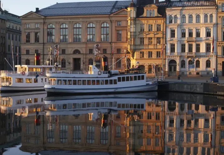 Fartyg i hamnen speglas i vattnet framför byggnader som vittnar om musikaliska Stockholm.