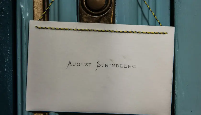 En skylt med texten "August Strindberg" hänger på en blå dörr, kanske vid Strindbergsmuseet.