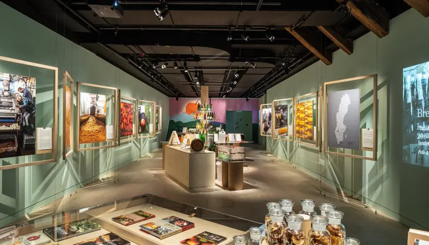 Utställning på Spritmuseum med bilder av produktion och ingredienser, samt flaskor med äppelmust.