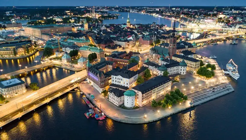 Vacker kvällsvy över Gamla Stan i Stockholm, Sverige. Upplysta byggnader och vatten reflekterar stadens ljus.