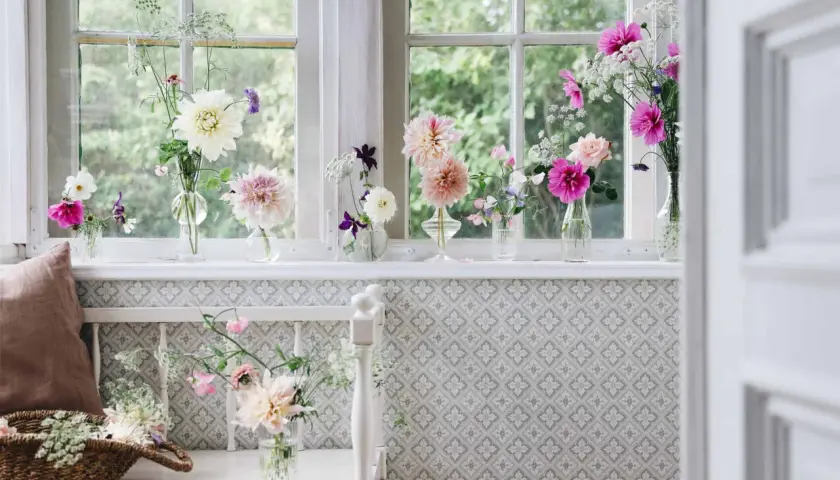 Vackra blommor i vaser pryder fönsterbrädan och skapar en inbjudande inredning.