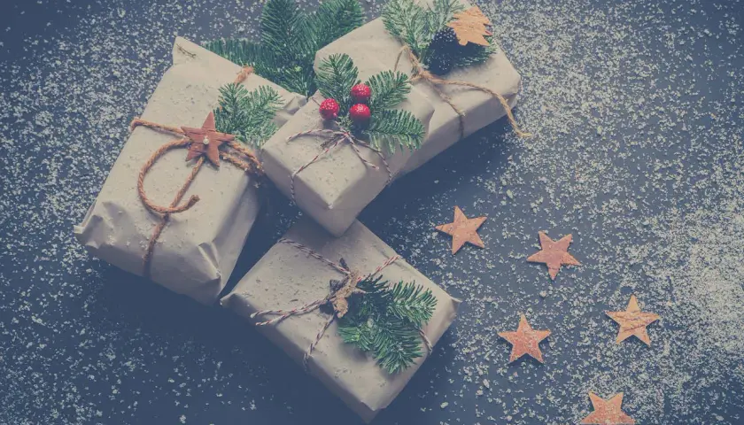 Julklappar inslagna i brunt papper, dekorerade med granris och stjärnor, redo för Siggesta Gård julmarknad.