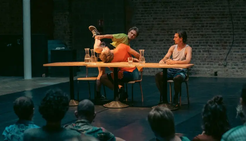 Akrobater på en scen vid ett bord, en del av föreställningen på Stockholm Fringe Festival.