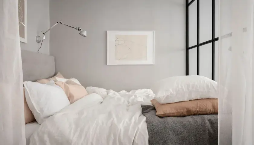 Sovalkov inspiration: Ett inbjudande sovrum med bäddad säng, vita sängkläder, rosa och vita kuddar, grå pläd och konst på väggen.