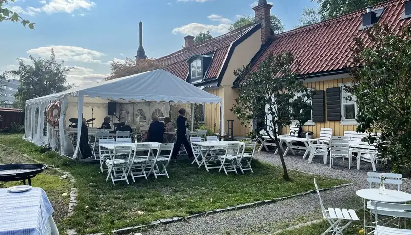 Festligt dukat utanför Ekermanska malmgården med tält, bord, stolar och ett liveband.