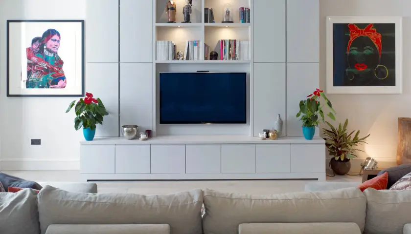Modernt tv-rum med en stor mediabänk, konstverk och bekväm soffa.