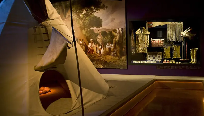 En utställning på etnologiska museet visar en tipi, en målning av ursprungsbefolkning och en samling kläder och föremål.