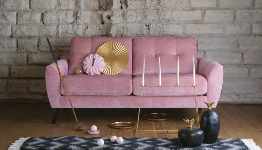 Rosa sammetssoffa med dekorativa föremål som ger soffa vardagsrum inspiration. En golfklubba, ljusstakar och ananasskulpturer skapar en unik atmosfär.
