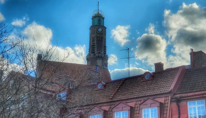 Engelbrekts kyrka reser sig mot en dramatisk himmel med moln. Kyrktornet har en klocka och en grön kupol.