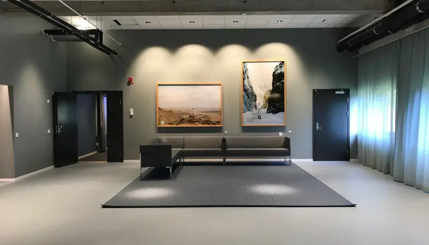 Väntrum med konstverk på väggarna, en soffgrupp och en matta. Kanske en del av konstakademien Stockholm.
