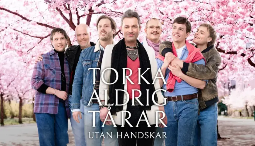 Sju män i en park med blommande körsbärsträd. Texten "Torka aldrig tårar utan handskar musikal" syns.