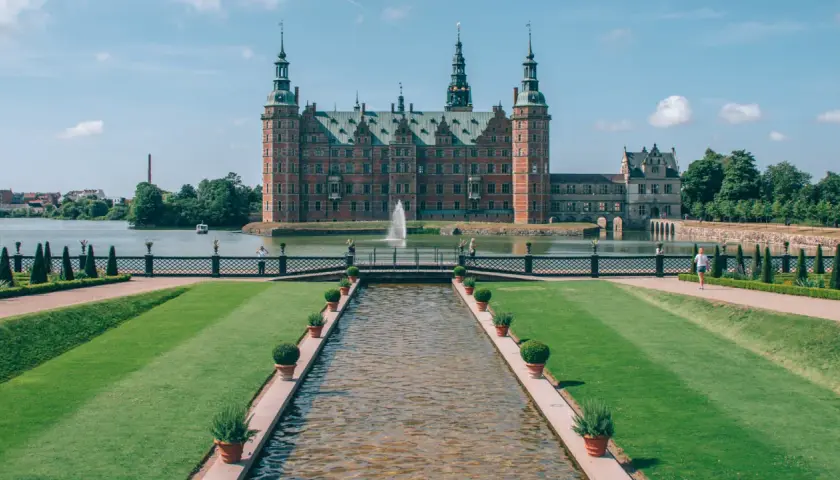 En imponerande utsikt över de kungliga slotten med en kanal som leder fram till en bro och slottet i bakgrunden.