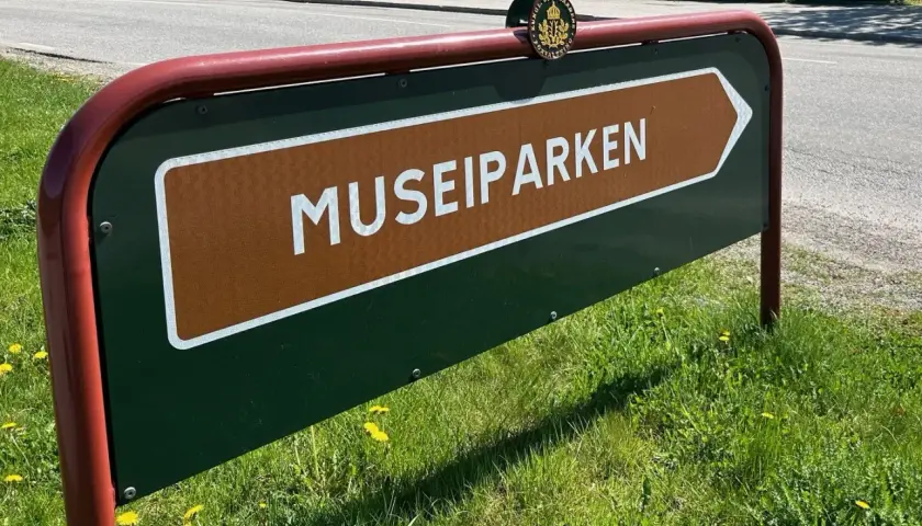 Skylt som pekar mot Museiparken Stockholm. En grön skylt med en brun pil och texten "MUSEIPARKEN" i vitt.