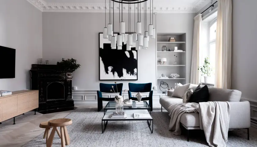 En modern skandinavisk inredning med en abstrakt skulptur som konstverk. En elegant taklampa och en svart öppen spis bidrar till rummets karaktär.